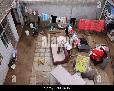 Baoding, chinesische Provinz Hebei. Aug. 2023. Die Dorfbewohnerin Zhao Guojin reinigt Möbel in ihrem Hof im Dorf Pingyu im Laishui County, nordchinesische Provinz Hebei, 17. August 2023. Laishui County hat durch die Auswirkungen des Taifuns Doksuri in letzter Zeit starke Niederschläge erlitten. Die lokalen Behörden haben aktiv den Wiederaufbau nach Katastrophen durchgeführt, um die Sicherheit der Bewohner zu gewährleisten und den von Überschwemmungen betroffenen Regionen wieder auf Kurs zu bringen. Quelle: Luo Xuefeng/Xinhua/Alamy Live News Stockfoto