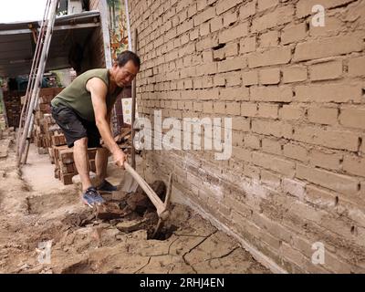 Baoding, chinesische Provinz Hebei. Aug. 2023. Der Dorfbewohner Zhao Minglin reinigt einen Entwässerungsgraben im Dorf Pingyu im Laishui County, nordchinesische Provinz Hebei, 17. August 2023. Laishui County hat durch die Auswirkungen des Taifuns Doksuri in letzter Zeit starke Niederschläge erlitten. Die lokalen Behörden haben aktiv den Wiederaufbau nach Katastrophen durchgeführt, um die Sicherheit der Bewohner zu gewährleisten und den von Überschwemmungen betroffenen Regionen wieder auf Kurs zu bringen. Quelle: Luo Xuefeng/Xinhua/Alamy Live News Stockfoto