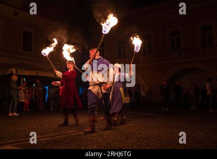 Zilina, Slowakische Republiс, Slowakei - 28. Juli 2023: Menschen in mittelalterlichen Kleidern und gepanzerten Rittern mit brennenden Fackeln während eines Feuers Stockfoto