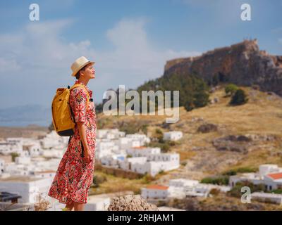 Schöne Glückliche Frau, Die Griechische Inseln Genießt. Reisen Sie nach Griechenland, Mittelmeerinseln außerhalb der Touristensaison. Genießen Sie Spaß bei der atemberaubenden Aussicht auf das Seebad und die Altstadt von Lindos auf den Bergen Stockfoto