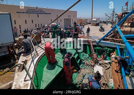 Essaouira, Marokko - 2. August 2023: Am Kai des Hafens bereiten sich die Männer eines Fischerbootes, das vom Meer zurückkehrt, darauf vor, den Fisch zu entladen, der zum Markt transportiert wird. Stockfoto