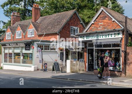 Leute, die im Sommer in ungewöhnlichen unabhängigen Geschäften in Burley Village im New Forest National Park, Hampshire, England, Großbritannien suchen Stockfoto