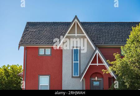 Häuser mit Schindeldach am blauen Himmel. Kante der Dachschindeln auf der Oberseite der Häuser dunkle Asphaltziegel auf dem Dach. Zeitgenössisches Haus. Fro Stockfoto