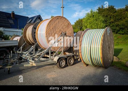 Große Rollen mit Glasfaserkabeln stehen auf einem Quadrat Stockfoto