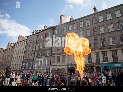 Royal Mile, Edinburgh, Schottland, Großbritannien. 17. August 2023. In dieser zweiten Woche des Edinburgh Festival Fringe war es ein farbenfroher Tag auf der High Street, an dem die verschiedenen Acts ihre Shows und die feurigen Straßenkünstler bewerben. Auf dem Bild: Der Straßenkünstler Chinnen aus Japan schlägt einen Feuerball, um seine Show auf der High Street abzuschließen. Quelle: Archwhite/Alamy Live News. Stockfoto