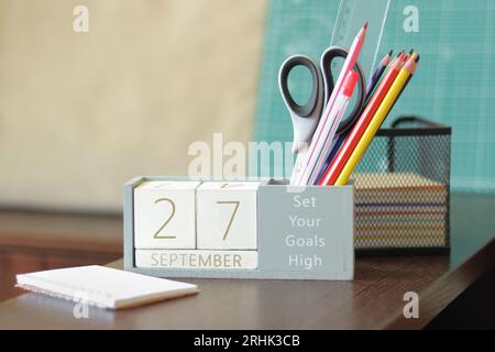 27. September. Bild von september 27 Holzkalender auf dem Desktop. Herbsttag. Zurück zur Schule. Bleistifte und Farben, Schreibwaren Stockfoto
