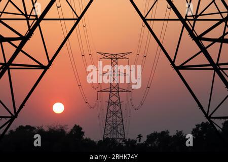 Blick auf den Sonnenuntergang hinter Hochspannungsleitungen Stockfoto