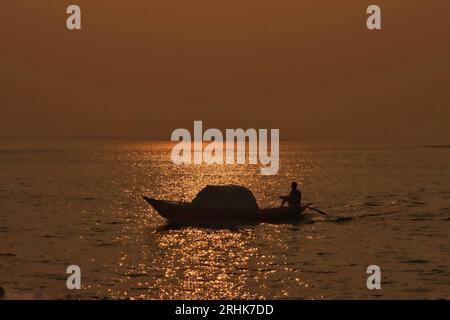 Ein Boot im Fluss Padma am späten Nachmittag, Silhouettenfoto Stockfoto