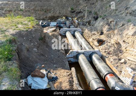 Unterirdische Grabenverlegung neuer Rohre im städtischen Wasser- und Heiznetz. Moderne Abwasserrohre aus Kunststoff, die nicht verrotten können. Stockfoto