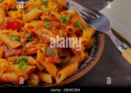 Sardinen und Pasta mit Gemüse und Tomatensoße, garniert mit Kräutern. Stockfoto