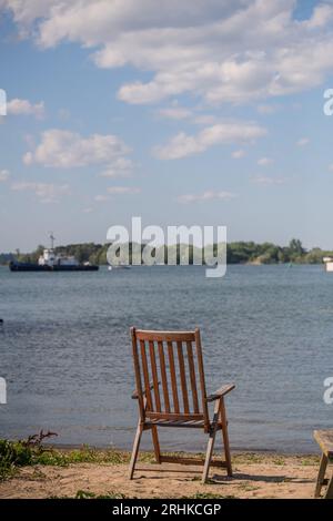 Ein leerer Holzstuhl am Strand mit Blick auf den Lake Ontario steht für einen erholsamen Urlaub in einem Ferienhaus und ein Gleichgewicht zwischen Berufs- und Privatleben Stockfoto