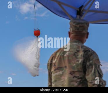 Lahaina, Vereinigte Staaten. August 2023. Ein CH-47 Chinook Hubschrauber der US-Armee wirft Meerwasser um den Rand des Gebietes, in dem Waldbrände über West Maui am 16. August 2023 in Lahaina, Maui, Hawaii fegten. Waldbrände, die durch starke Winde angefacht wurden, töteten mindestens 100 Menschen und zerstörten Tausende von Häusern auf der Insel. Credit: SPC. Tonia Ciancanelli/USA Nationalgarde/Alamy Live News Stockfoto