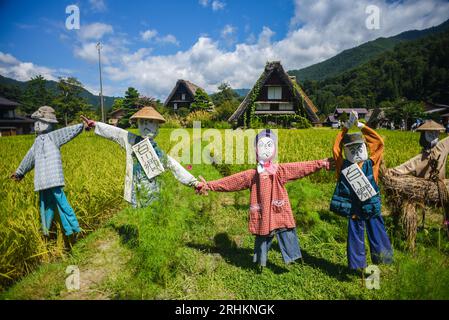 Vogelscheuchen vor den traditionellen Gassho-zukuri Strohhütten aus Holz im Dorf Shirakawa-Go, Präfektur Gifu, Japan Stockfoto