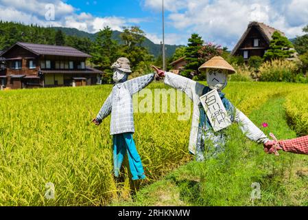 Vogelscheuchen vor den traditionellen Gassho-zukuri Strohhütten aus Holz im Dorf Shirakawa-Go, Präfektur Gifu, Japan Stockfoto