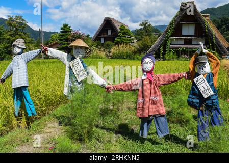 Vogelscheuchen vor den traditionellen Gassho-zukuri Strohhütten aus Holz im Dorf Shirakawa-Go, Präfektur Gifu, Japan Stockfoto