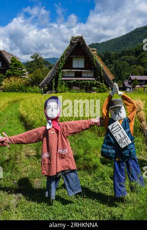 Vogelscheuchen vor den traditionellen Gassho-zukuri Strohhütten aus Holz im Dorf Shirakawa-Go, Präfektur Gifu, Japan Stockfoto