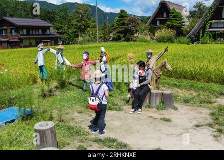 Vogelscheuchen vor den traditionellen Gassho-zukuri Strohhütten aus Holz im Dorf Shirakawa-Go, Präfektur Gifu, Japan Stockfoto