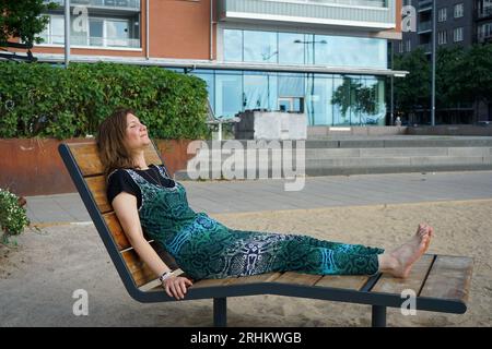 Eine Person, die auf einer Bank in der Stadt ruht Stockfoto