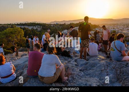 Athen, GR - 29. Juli 2023: Menschen, die den Sonnenuntergang auf dem Areopagus-Hügel betrachten Stockfoto