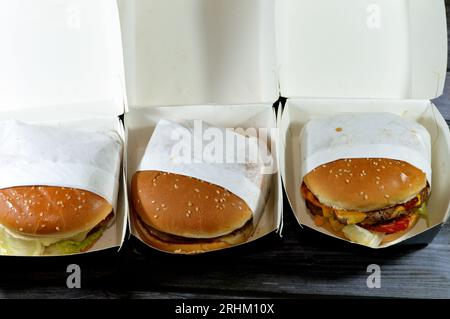 Haufen Sesambrötchen mit frittierten panierten Hähnchenfilet-Pattys, knackigem Salat, Schmelzkäse, Zwiebeln und Sauce, saftigem, dickem, doppeltem Rinderpatty mit Chees Stockfoto