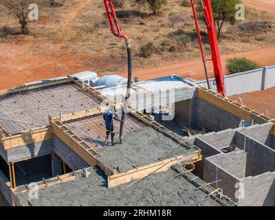 afrikanische Bauarbeiter in der Stadt auf der Baustelle, die den Grundstein eines Gebäudes mit einer Betonpumpe füllen Stockfoto