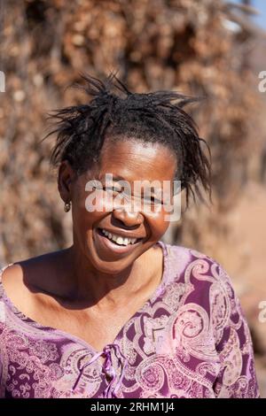 afrikanische Frau im Dorf, die im Hinterhof steht, mit einem lächelnden Gesicht in der hellen Sonne Stockfoto