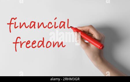 Frau schreibt Worte Financial Freedom auf weißem Hintergrund, Draufsicht Stockfoto