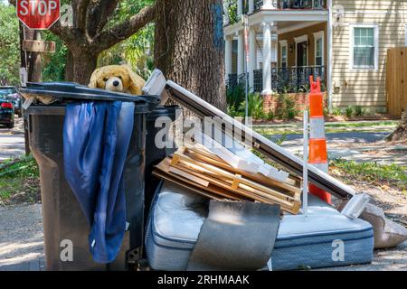 NEW ORLEANS, LA, USA - 16. AUGUST 2023: Stofftiere, Matratzen und andere weggeworfene Gegenstände, die in und um Mülltonnen auf der Bordsteinkante zurückbleiben Stockfoto