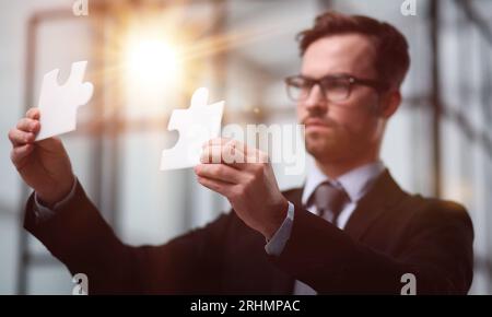 Business-Puzzle, Strategie und Marketing. Geschäftsmann zeigt silberne Teil des Puzzles Stockfoto