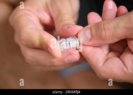 Man-Hand-Befestigung des Netzkabels am RJ45-Steckverbinder. Stockfoto