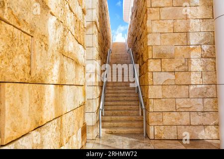 Stufen in einer schmalen Passage zwischen Mauern, die in Richtung des leuchtend blauen Himmels führen. Stockfoto