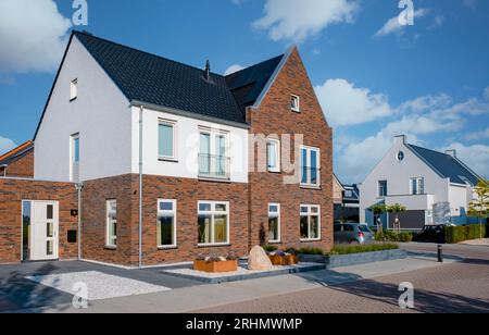 Holländisches Vorstadtviertel mit modernen Einfamilienhäusern, neu gebauten modernen Einfamilienhäusern in den Niederlanden, holländischem Einfamilienhaus in den Niederlanden, Reihe moderner Häuser in zeitgenössischem Viertel Stockfoto