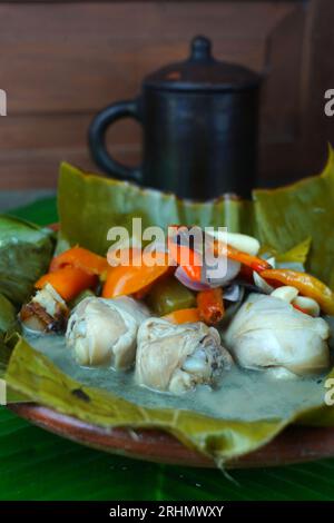 Garang ASEM, das traditionelle javanische Essen, wird auf einem Tonteller serviert, der mit Bananenblättern gesäumt ist und von einer Mischung aus Vogelaugen-Chili und Tomate begleitet wird Stockfoto