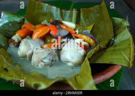 Garang ASEM, das traditionelle javanische Essen, wird auf einem Tonteller serviert, der mit Bananenblättern gesäumt ist und von einer Mischung aus Vogelaugen-Chili und Tomate begleitet wird Stockfoto