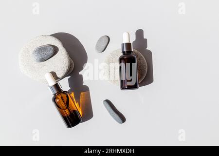 Ein natürliches Bio-Kosmetikprodukt in zwei Flaschen, die auf flachen grauen ovalen Steinen liegen. Draufsicht. Ein leeres Etikettenpaket zum Branding des Layouts Stockfoto