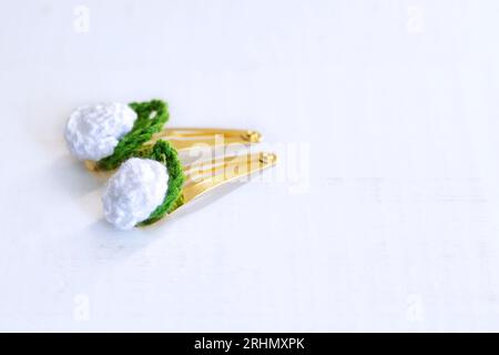 Weiße Blumen mit Häkelarbeit, als Haarspangen, auf einem alten weißen Holztisch mit Kopierraum. Stockfoto