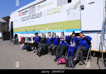 Kapstadt, Südafrika. Aug. 2023. Die Schüler stehen am 10. August 2023 in de Aar Town, mehr als 750 Kilometer nordöstlich von Kapstadt, Südafrika, vor einem medizinischen Bus, der auf eine Untersuchung wartet. Die medizinischen Bedingungen in de Aar sind rückläufig. 2020 kaufte Longyuan South Africa Renewables of China Longyuan Power Group Corporation Limited einen professionellen medizinischen Bus, der mit Geräten und medizinischem Personal ausgestattet war, um den Einwohnern seitdem kostenlosen Service zu bieten. Kredit: Dong Jianghui/Xinhua/Alamy Live News Stockfoto