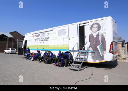 Kapstadt, Südafrika. Aug. 2023. Die Schüler stehen am 10. August 2023 in de Aar Town, mehr als 750 Kilometer nordöstlich von Kapstadt, Südafrika, vor einem medizinischen Bus, der auf eine Untersuchung wartet. Die medizinischen Bedingungen in de Aar sind rückläufig. 2020 kaufte Longyuan South Africa Renewables of China Longyuan Power Group Corporation Limited einen professionellen medizinischen Bus, der mit Geräten und medizinischem Personal ausgestattet war, um den Einwohnern seitdem kostenlosen Service zu bieten. Kredit: Dong Jianghui/Xinhua/Alamy Live News Stockfoto