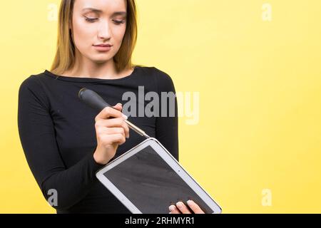 Service-Center. Laptop-Reparatur. Schraubendreher mit Innengewinde löst Laptopschrauben auf gelbem Hintergrund Stockfoto