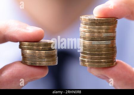 Mann mit zwei Münzen Stapeln zu vergleichen. Stockfoto