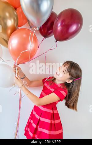 Ein zehnjähriges Mädchen, umgeben von Geburtstagsballons Stockfoto