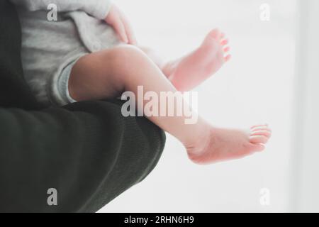 Elternteil hält Baby, Nahaufnahme von Beinen und Füßen des Babys Stockfoto