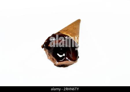 Eis aus cremiger Kakaoschokolade mit Schokoladensauce und Brownie-Stücken in knusprigen Waffelkonen, schmelzendes kaltes Eis in A Stockfoto