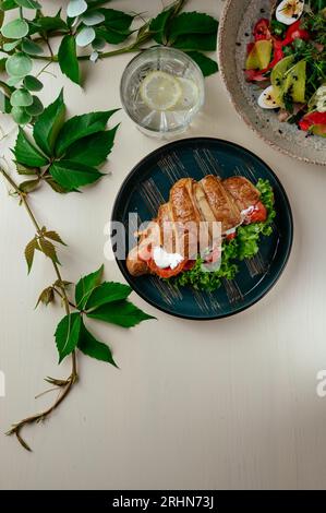Croissant mit Frischkäse, Lachs, Gemüse und Kräutern. Ruhe Stockfoto