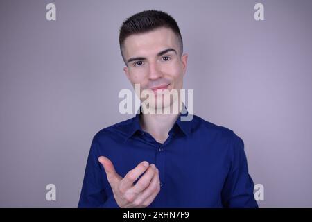 Eleganter und schöner junger kaukasischer Mann mit unsichtbarem Objekt auf isoliertem Hintergrund Stockfoto