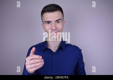 Eleganter und schöner junger kaukasischer Mann mit unsichtbarem Objekt auf isoliertem Hintergrund Stockfoto