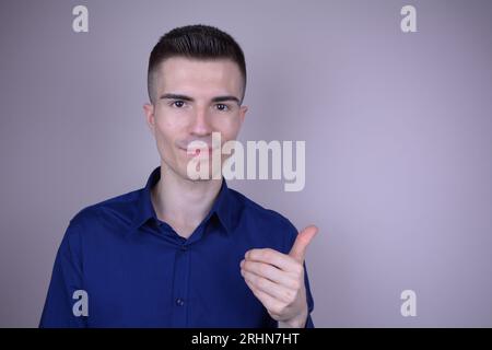 Eleganter und schöner junger kaukasischer Mann mit unsichtbarem Objekt auf isoliertem Hintergrund Stockfoto