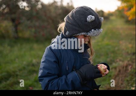 Seitenansicht eines Jungen mit Winterhut und Mantel, der Apfel hält Stockfoto