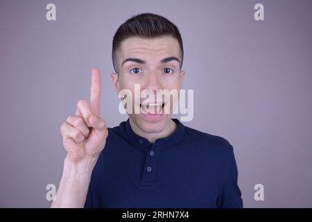 Lächelnder junger gutaussehender Kaukasier zeigt mit brillanter Ideengeste auf isoliertem Hintergrund Stockfoto