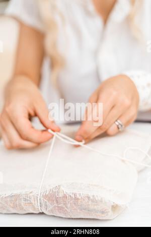 Eine Frau, die ein Paket mit Leinentuch und Schnur verbindet Stockfoto